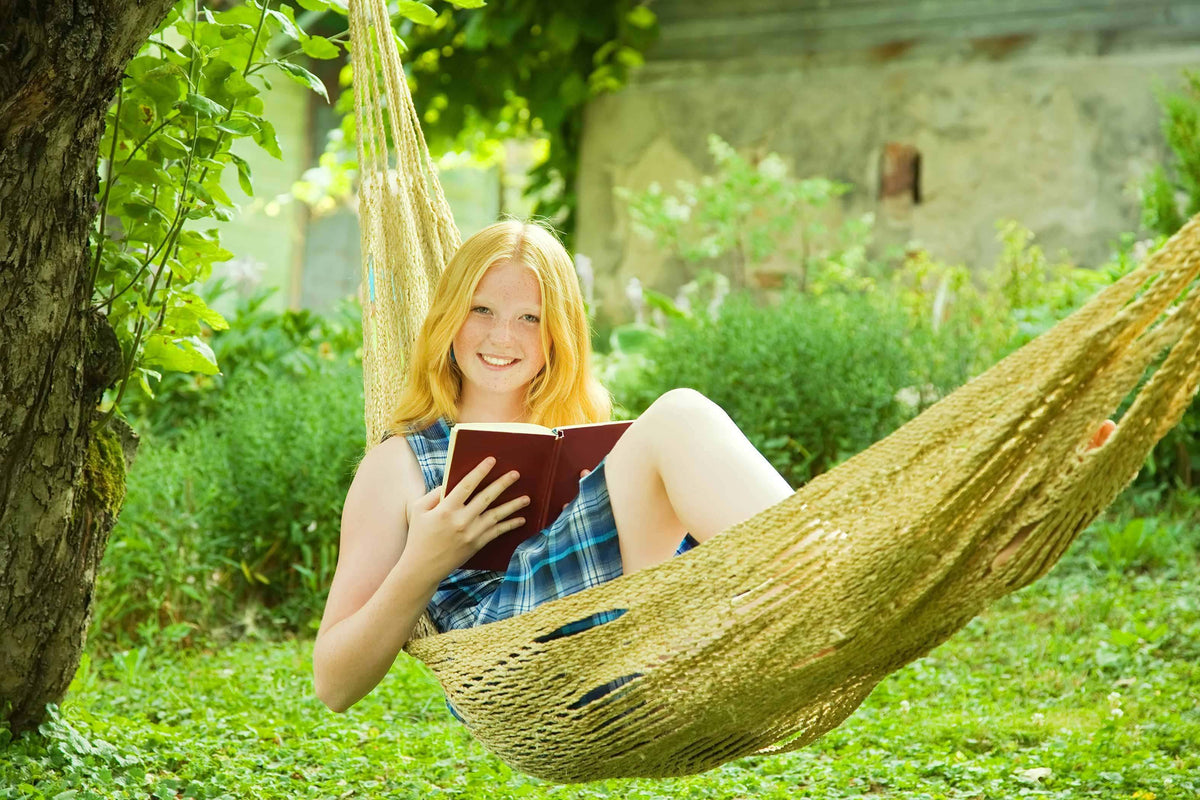 Девушка в гамаке читает книгу