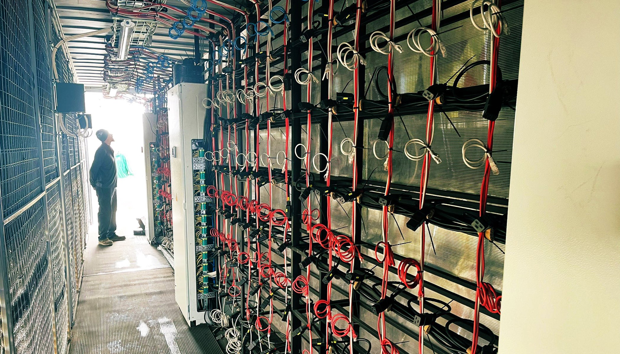 Technician study the wire configuration inside a containerized mining unit. 