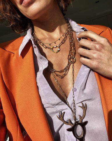 Silk shirt, orange blazer and deer pendant mixed with various gold chains