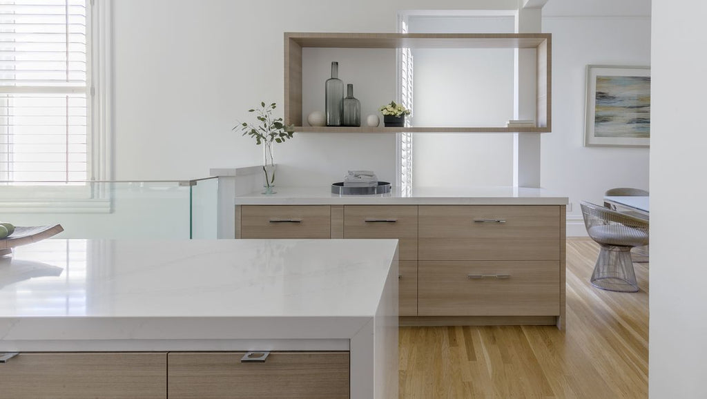 Modern kitchen featuring white space and light wooden cabinetry with minimalist decor and clean line design.