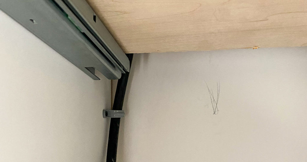 A DIY drawer outlet solution with an unprotected cord behind the drawer box.