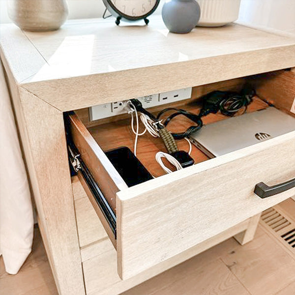 Docking drawer outlet charging a smartphone, smartwatch, and laptop in a nightstand drawer.