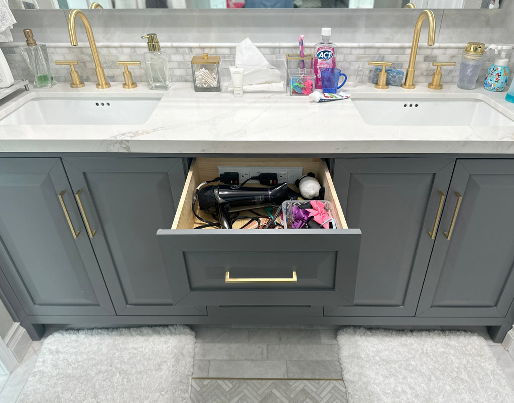 A modern bathroom vanity with an open drawer, showing a hair dryer plugged into a Docking Drawer Blade Duo outlet.