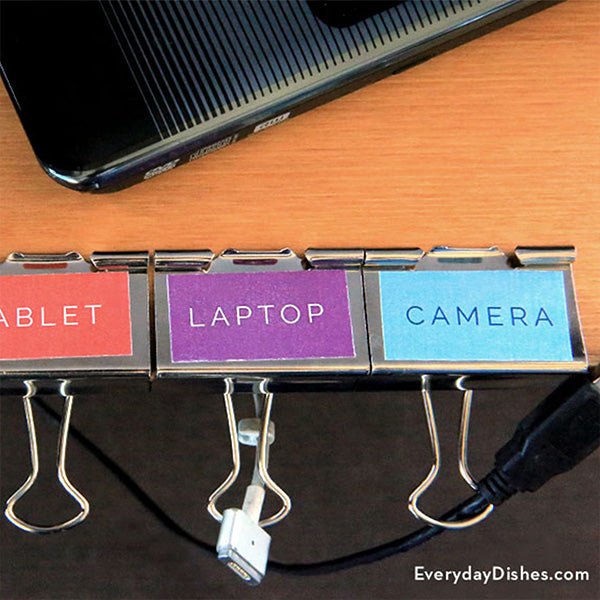 Four binder clips with colored labels holding the end of various device cords.