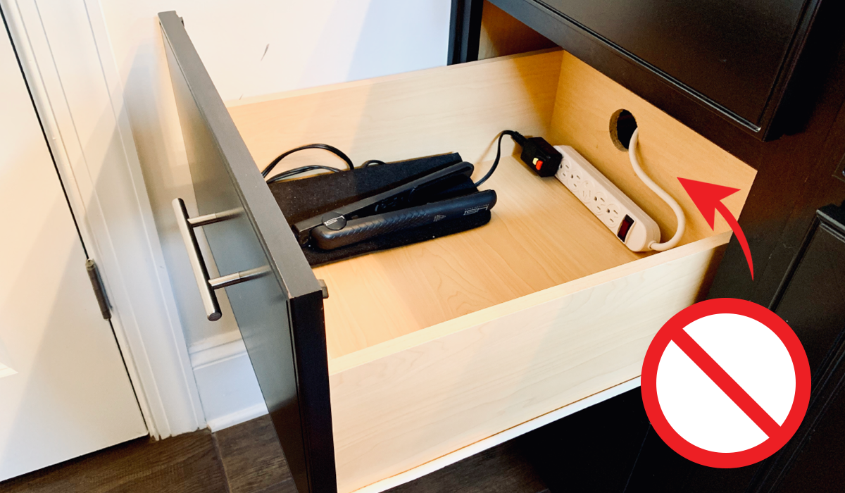 A DIY drawer power strip solution unsafely installed into a bathroom drawer powering a hair straightener.
