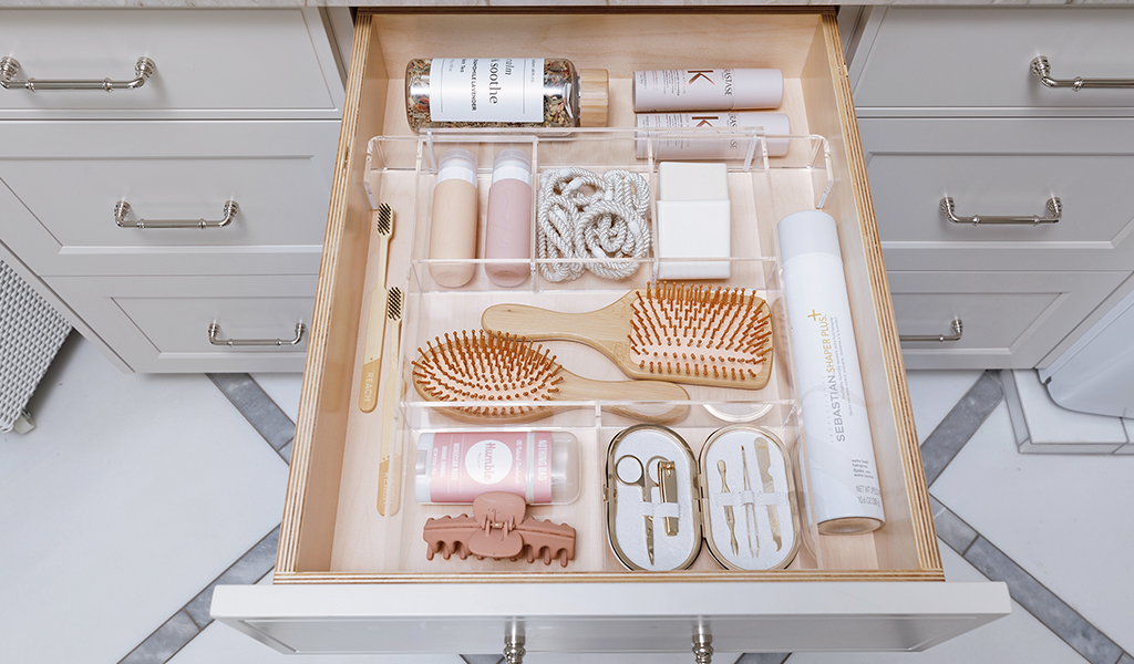 Large bathroom drawer with a wide drawer organizer storing a nail kit, hair ties, and other accessories.