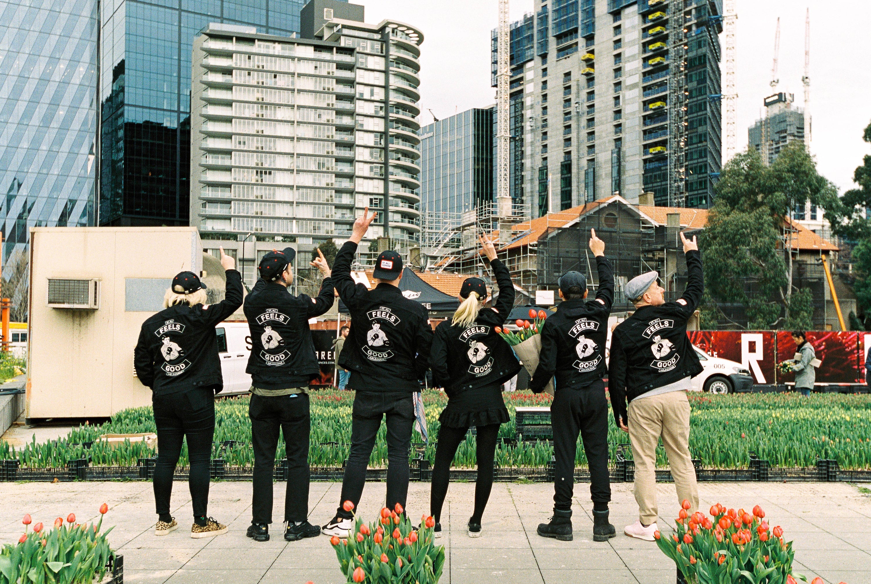 people gesturing while facing the city wearing black jackets
