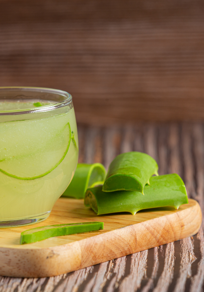 Aloe vera juice with leaves on a wooden table with numerous skin benefits.