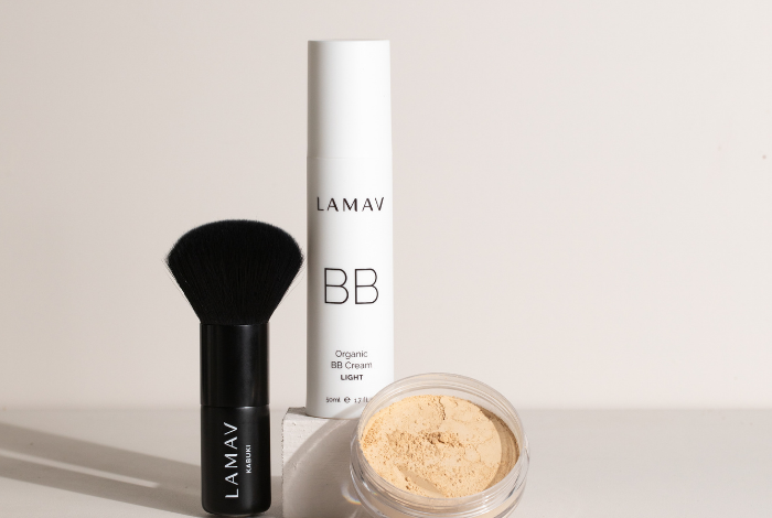 Next to the foundation, the BB powder and brush are placed, highlighting the organic BB cream's role as a natural sunscreen