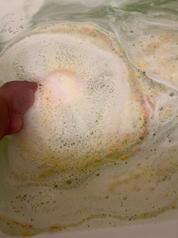 Bath bomb fizz foaming water releasing juicy pear scent and plant based ingredients for a fun and moisturizing bath for kids