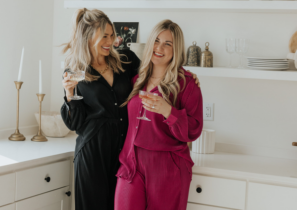Two girls in coordinating sets drinking champagne and laughing