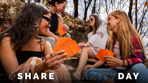 share humanity day. People playing the and card game together outside