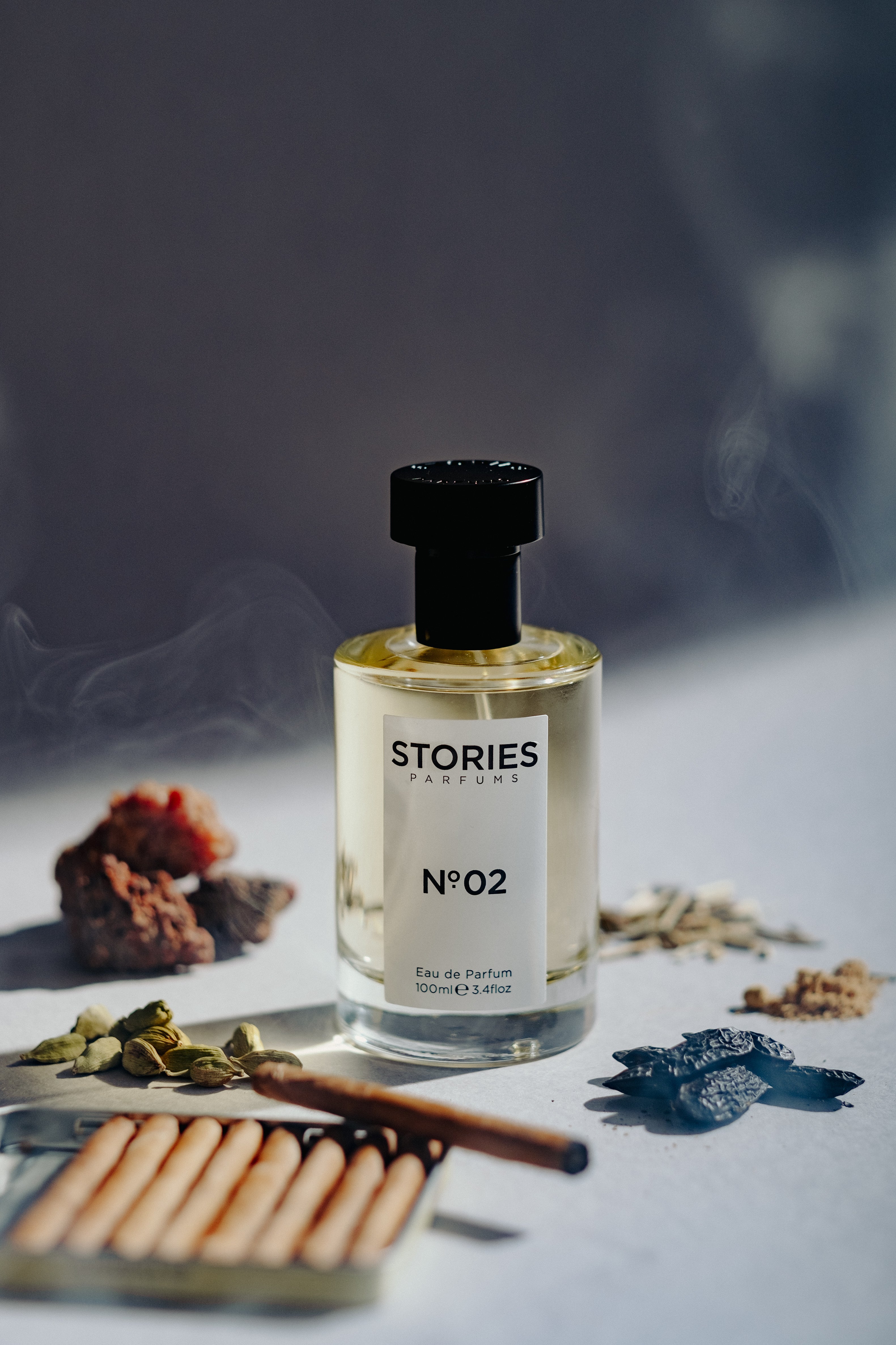 STORIES No.02 with ingredients and lit cigar with plume of smoke