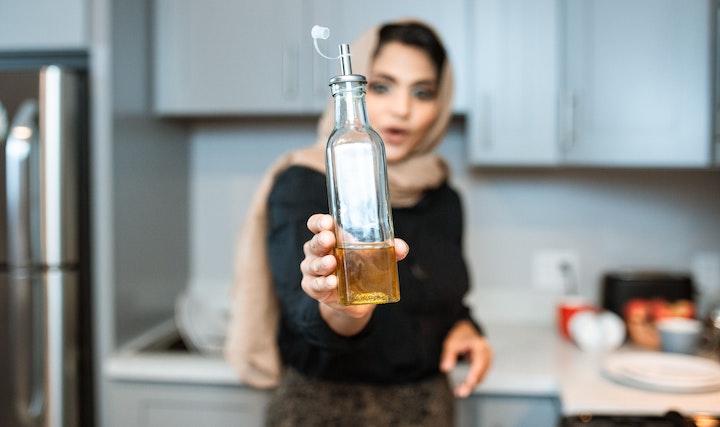donna araba con bottiglia di olio - pexels