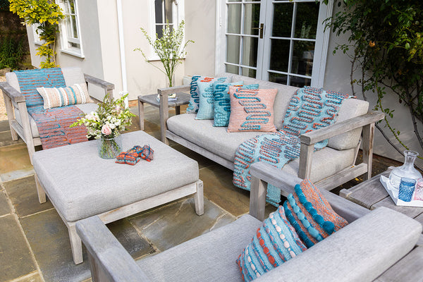 An outdoor sitting room featuring handwoven throws and cushions from the West Coast Collection