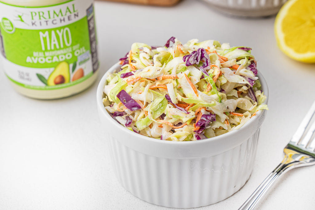 Coleslaw side in a small side dish in front of a jar of Primal Kitchen Mayo