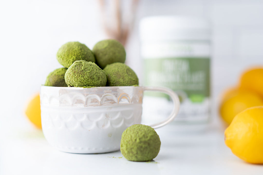 A white cup of Lemon Matcha Collagen Balls, with a canister of Primal Kitchen Collagen in the background.. 