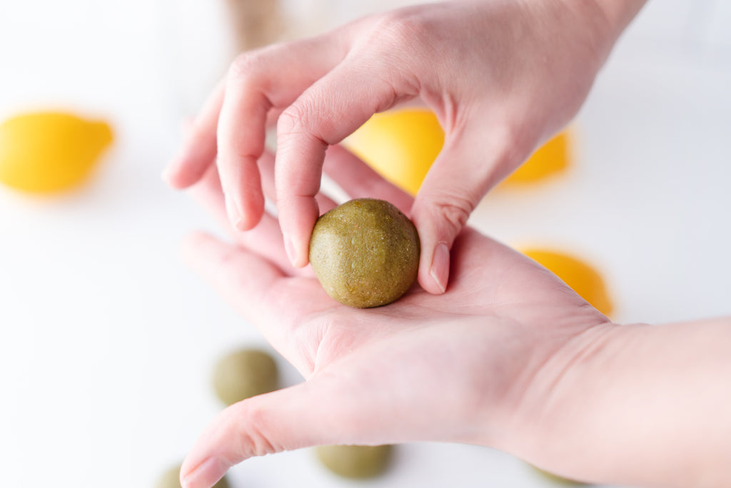 A hand holding a matcha ball after rolling it into a ball