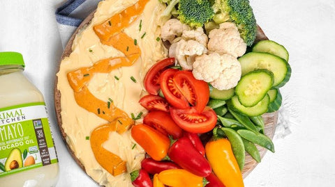 A wooden board slathered with Primal Kitchen Mayo and piled with fresh veggies. 