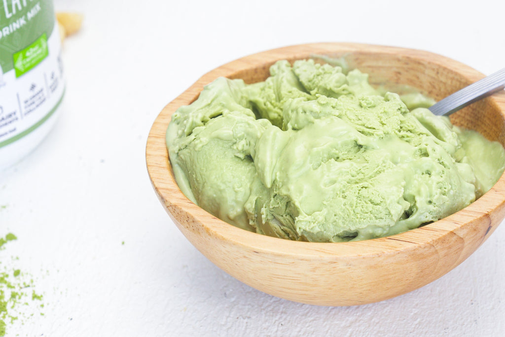 A wooden bowl of matcha ice cream with a can of Primal Kitchen Collagen Peptides in the background