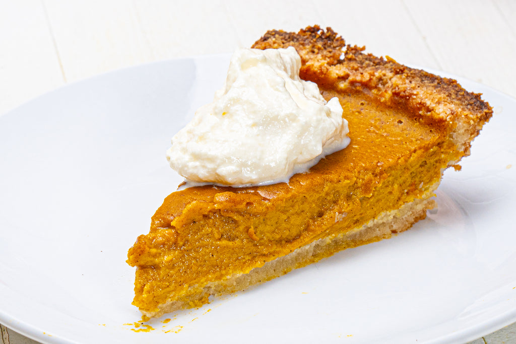 pumpkin pie with whipped cream on a white plate
