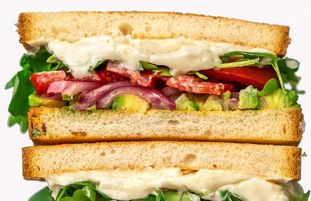 A close up of a vegan mayo veggies sandwich cut in half.