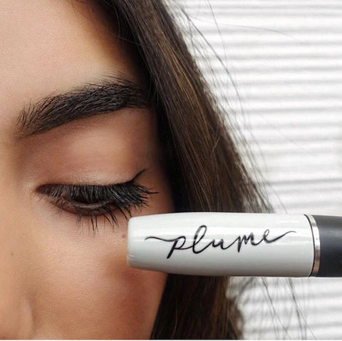 Image of woman holding Plume Lash and Brow Enhancing Serum near her long eyelashes on well&belle