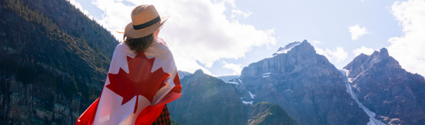 Woman wrapped in Canadian flag looking at Rocky Mountains