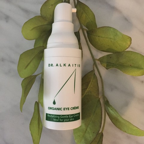 Image of Dr. Alkaitis eye cream on top of leaves on marble surface, on well&belle