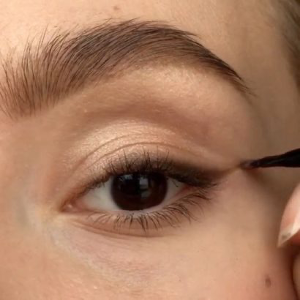 Closeup of woman applying kitten eye eyeliner with a small makeup brush