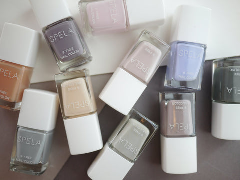 image of several Spela nail polish bottles randomly placed on a grey and white flat surface on well&belle