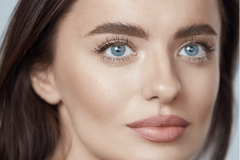 Beautiful woman with blue eyes, dewy skin, long lashes, full brows, lined lips