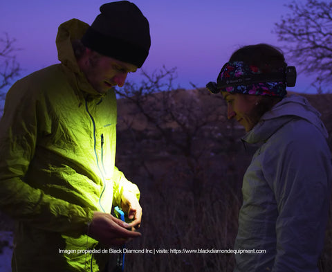 Corredores de trail running cambiando las baterias de su headlamp en un bosque de noche