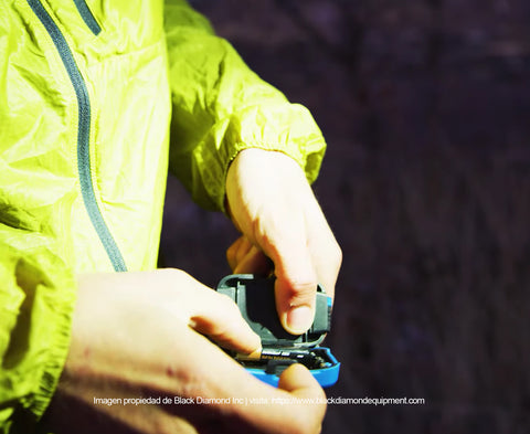 Corredor de trail running acomodando las baterias dentro de su headlamp debajo del halo de luz de una compañera corredora que lo acompaña