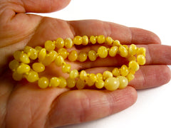 amber teething necklace in hand, milky yellow egg yolk, healing beads, for drooling