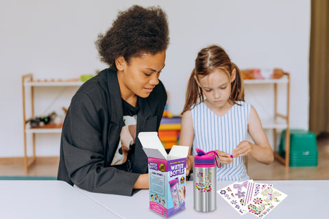 girl and teacher decorating water bottle