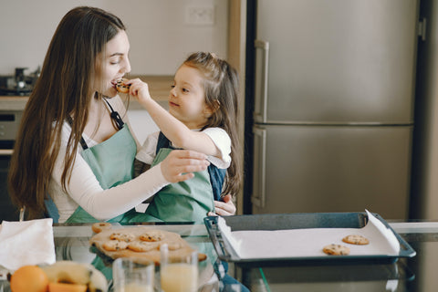 girl baking cookies with mom