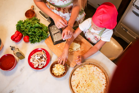 girl baking pizza with mom