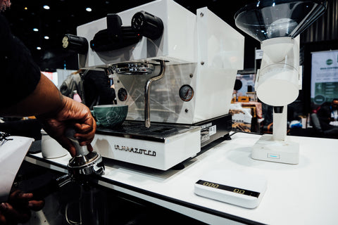 Acaia team member pulling shot of espresso next to a white orbit and white lunar scale