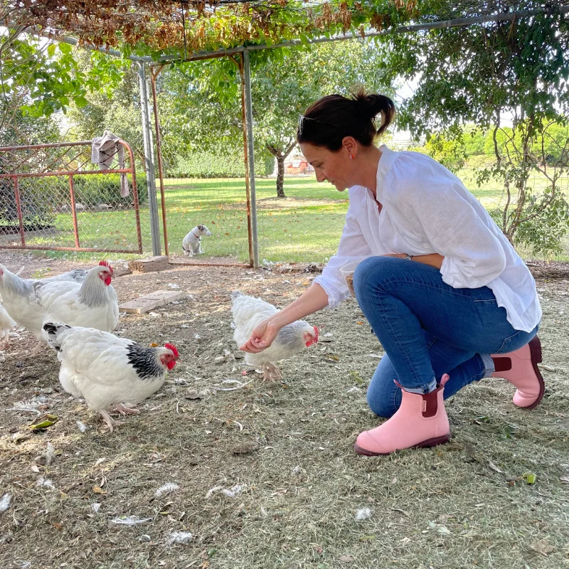 feeding the chicken with dusty pink boots on