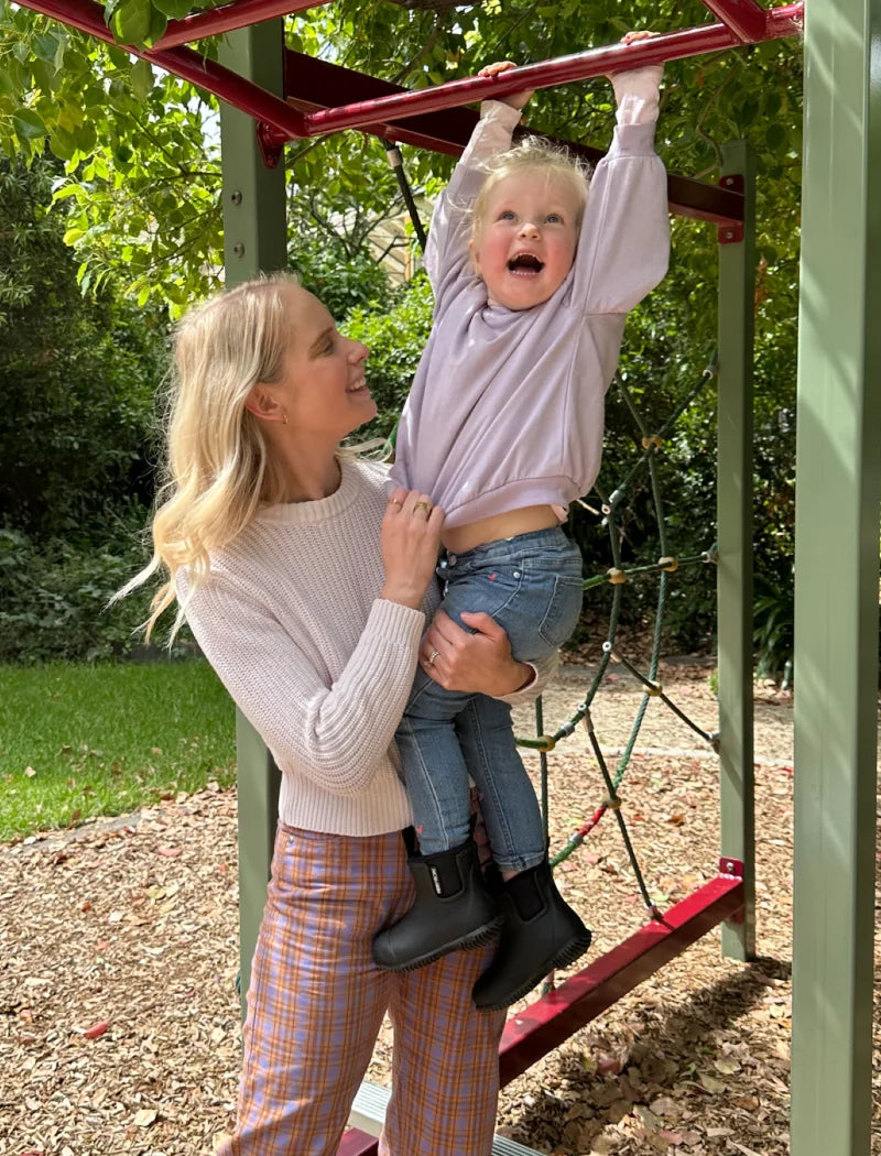 kid hanging on the bar with mother