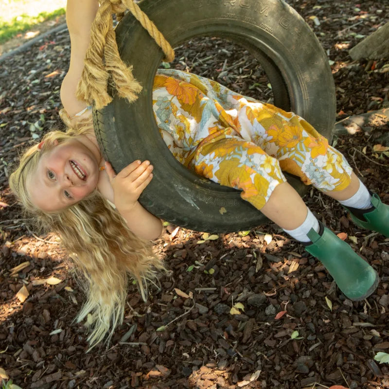 kid playing in the park with green boots