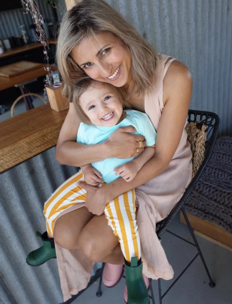 mother holding daughter wearing green and pink boots