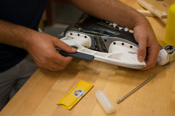 Person using skate stone on a hockey skate