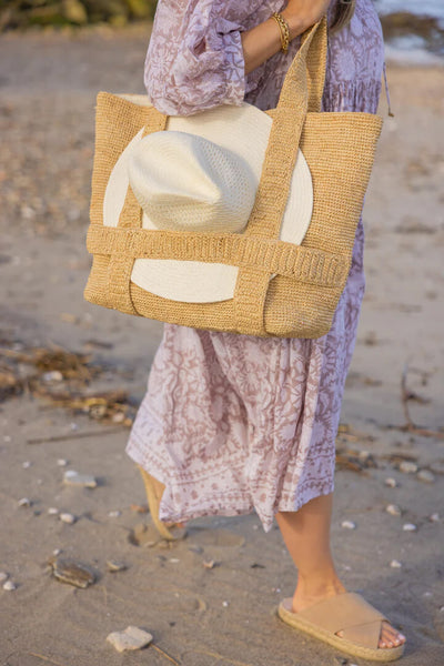 White straw tote bag over a woman's shoulder.