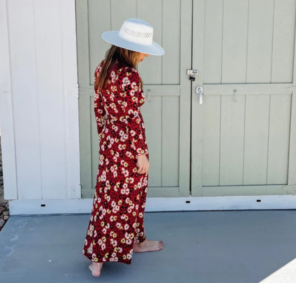 Woman wearing long red dress and wite summer straw sunhat.