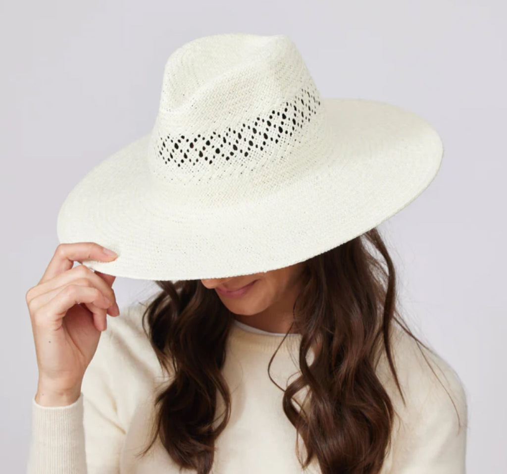 Woman wearing and holding white sunhat.