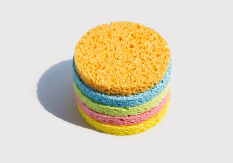 A stack of colorful circular sponges in yellow, blue, pink, and green, on a white background.