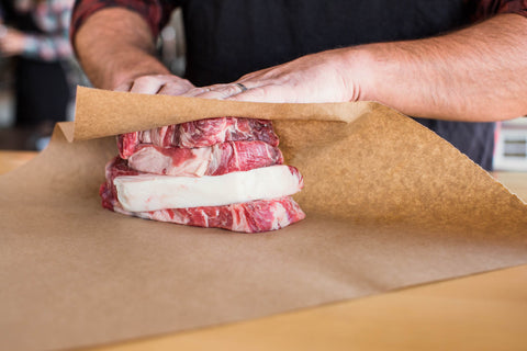 Butcher wrapping freshly cut beef