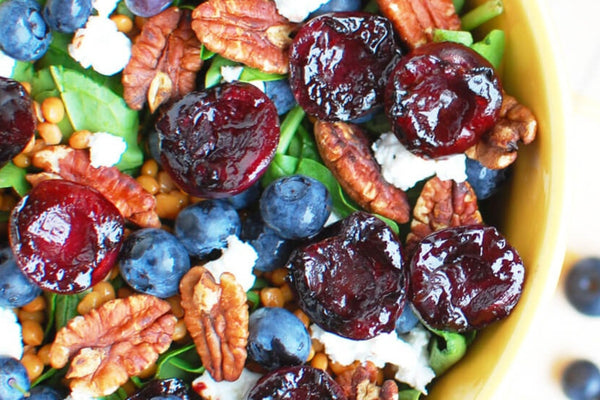 BBQ balsamic grilled cherry, goats cheese and green lentil spinach salad in a bowl on a white kitchen worktop